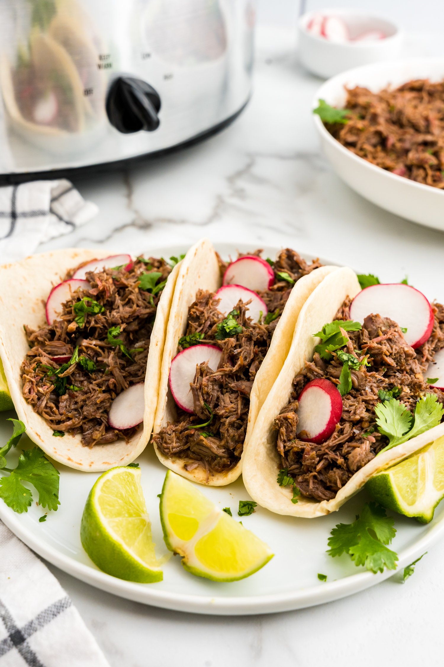 Barbacoa Beef in tortillas loaded with all the fixings on a plate