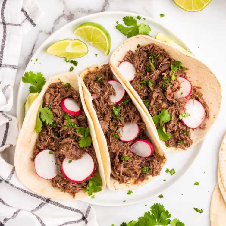 Barbacoa Beef in tortillas with fixings on plate