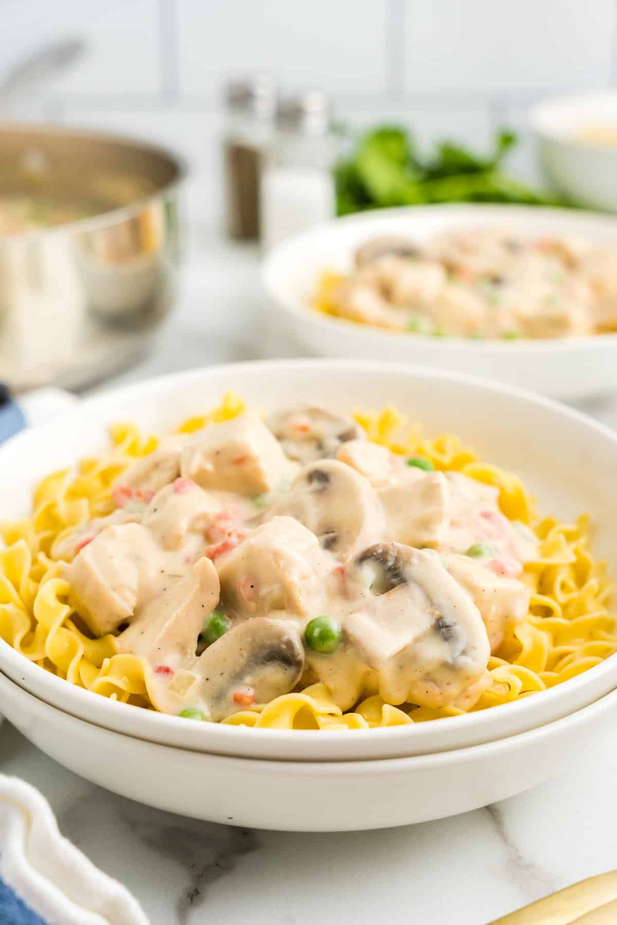 Serving Chicken a la King over egg noodles in shallow serving bowl