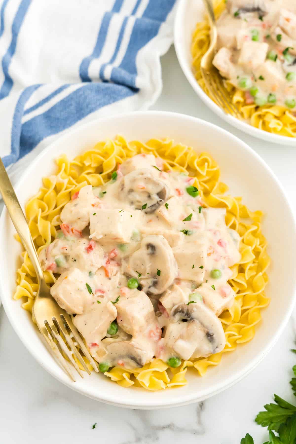 Chicken ala King recipe over egg noodles in serving bowl with fork