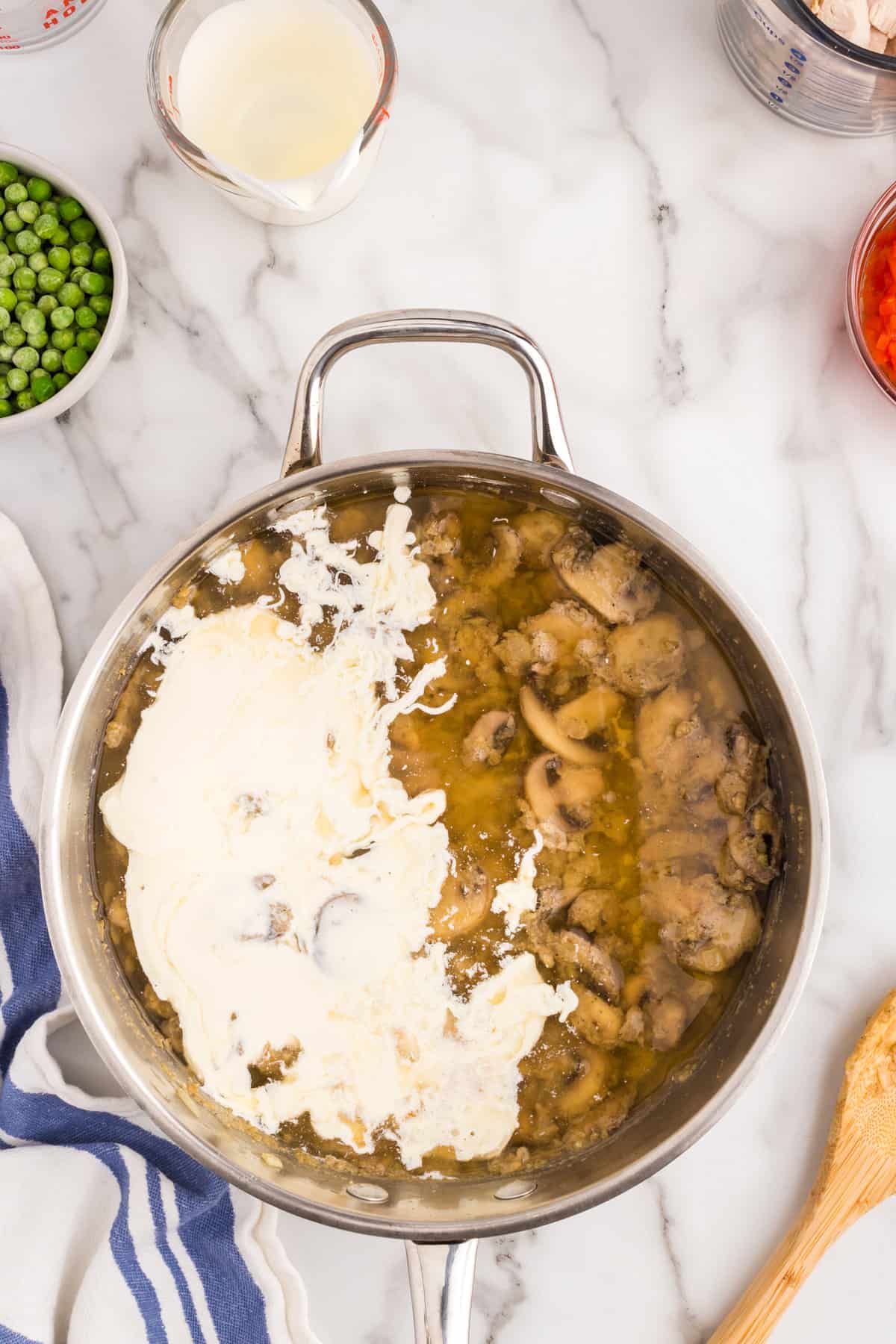 Addding heavy cream to ingredients for Chicken ala King recipe in stovetop skillet