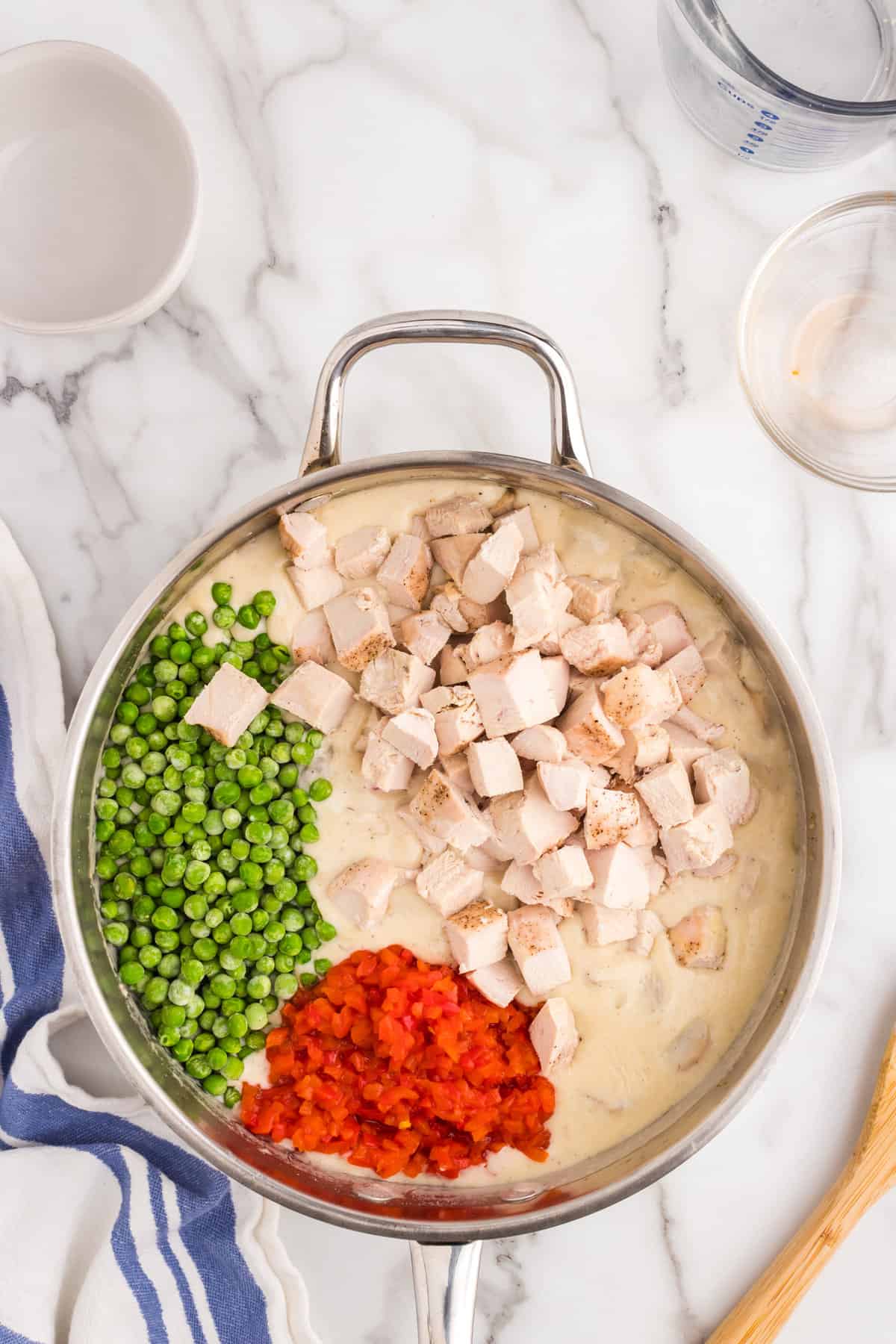Adding chicken, peas, and pimentos to mixture in skillet for Chicken a la King recipe