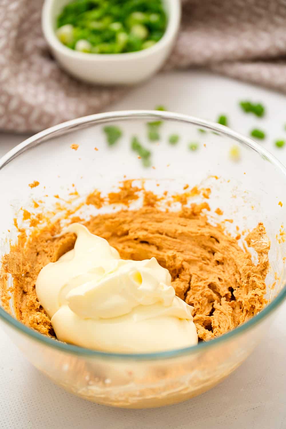 Glass bowl with cream cheese and taco seasoning mixed together and mayo added