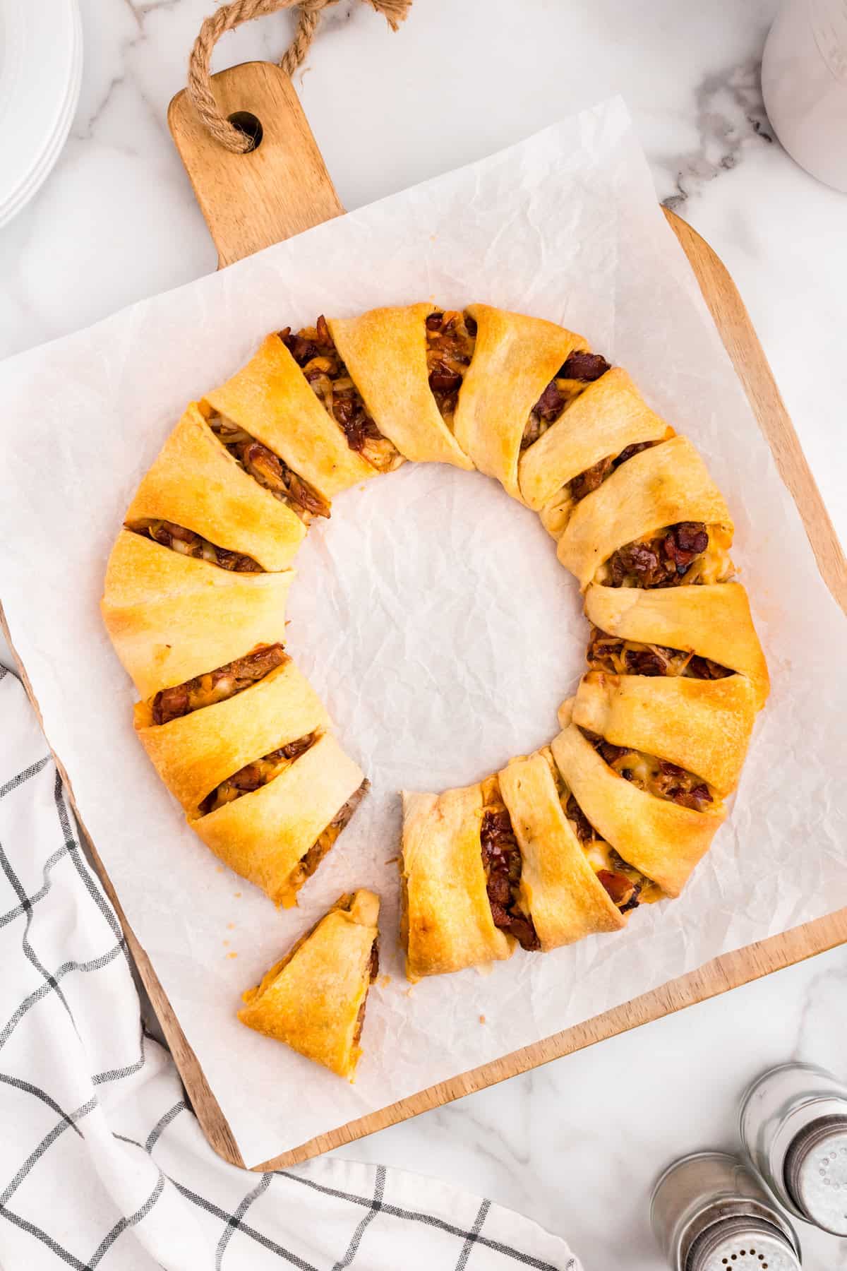 Pulled Pork Crescent Ring with one slice cut and removed on parchment paper