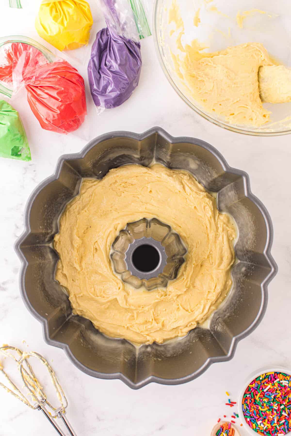 Grease your Bundt pan and add a layer of non colored cake mix to the bottom.