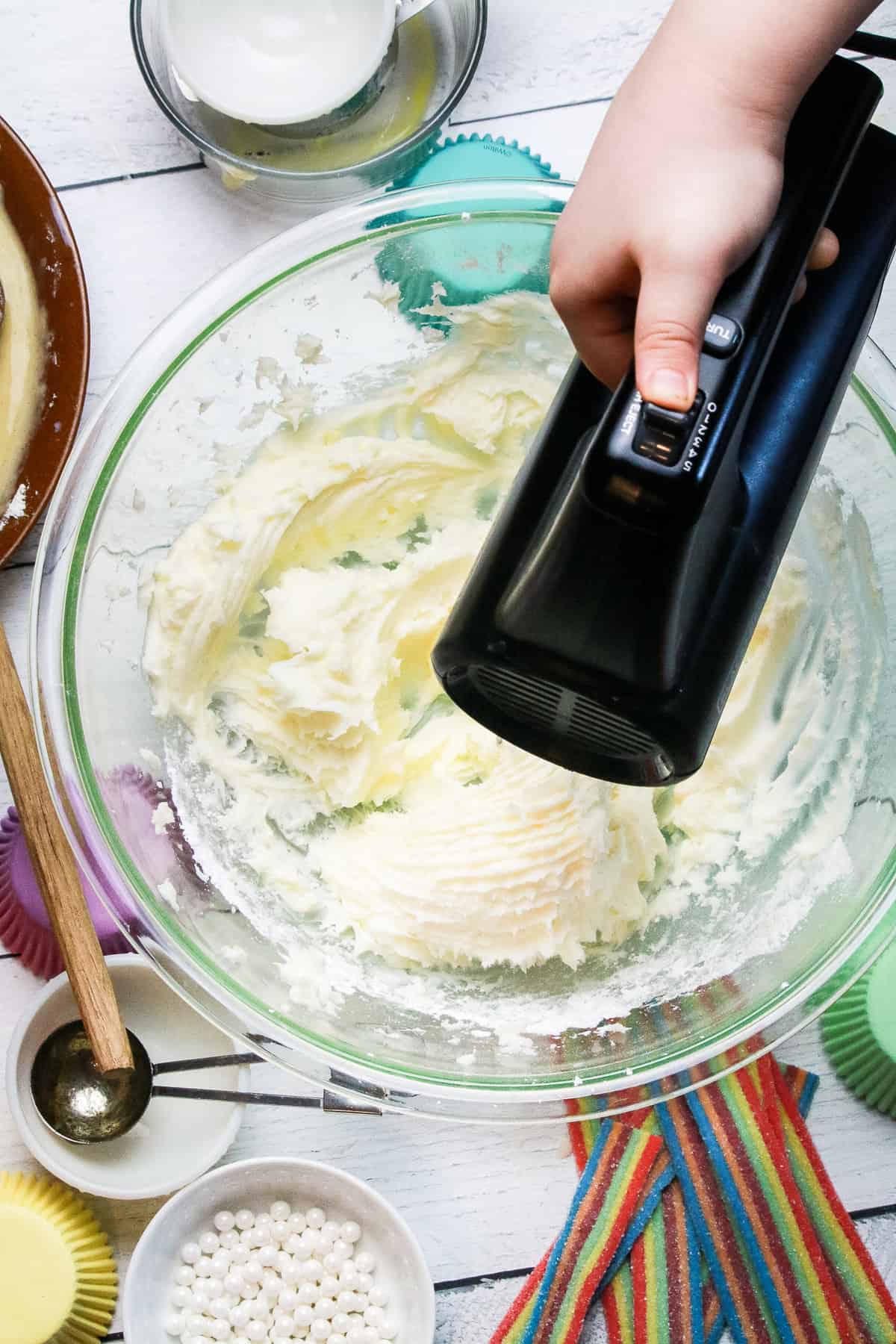 Prepare the buttercream frosting. Add two sticks of softened butter into a large bowl. Sift four cups of powdered sugar on top of the butter. Using a hand mixer on low speed.