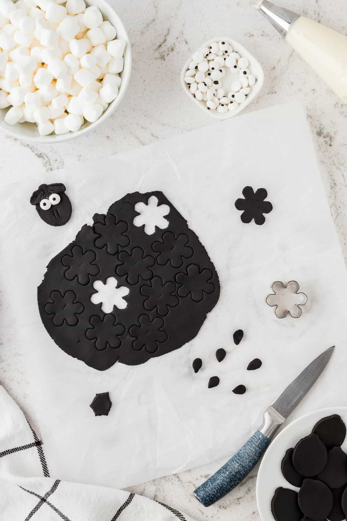 Next, use a small snowflake cookie cutter to make the sheep's ears and modified their shape by cutting and molding.