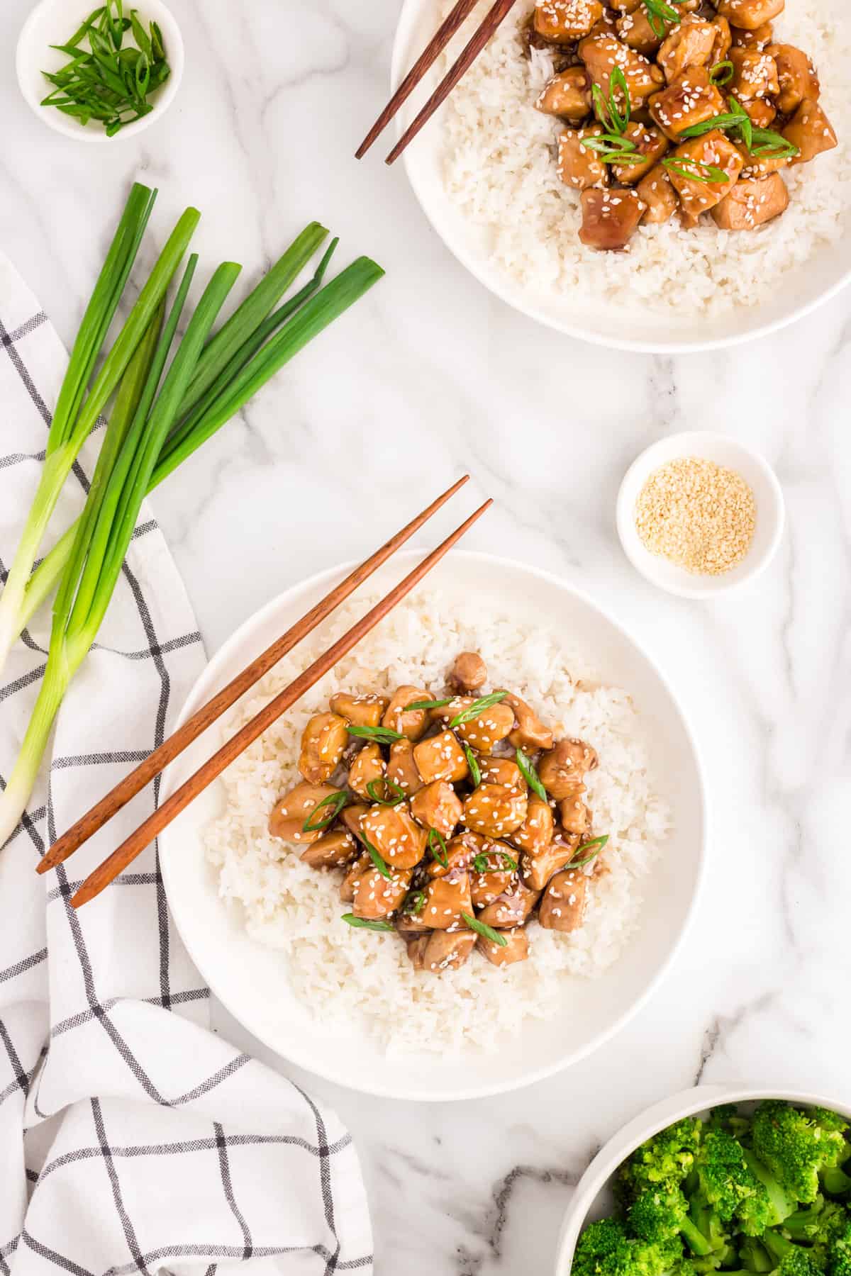 Teriyaki Chicken on top of a bed of white rice in shallow serving bowl with chop sticks