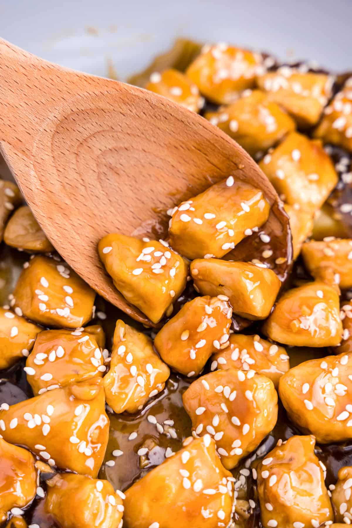 Using wooden spoon to scoop Teriyaki Chicken for serving