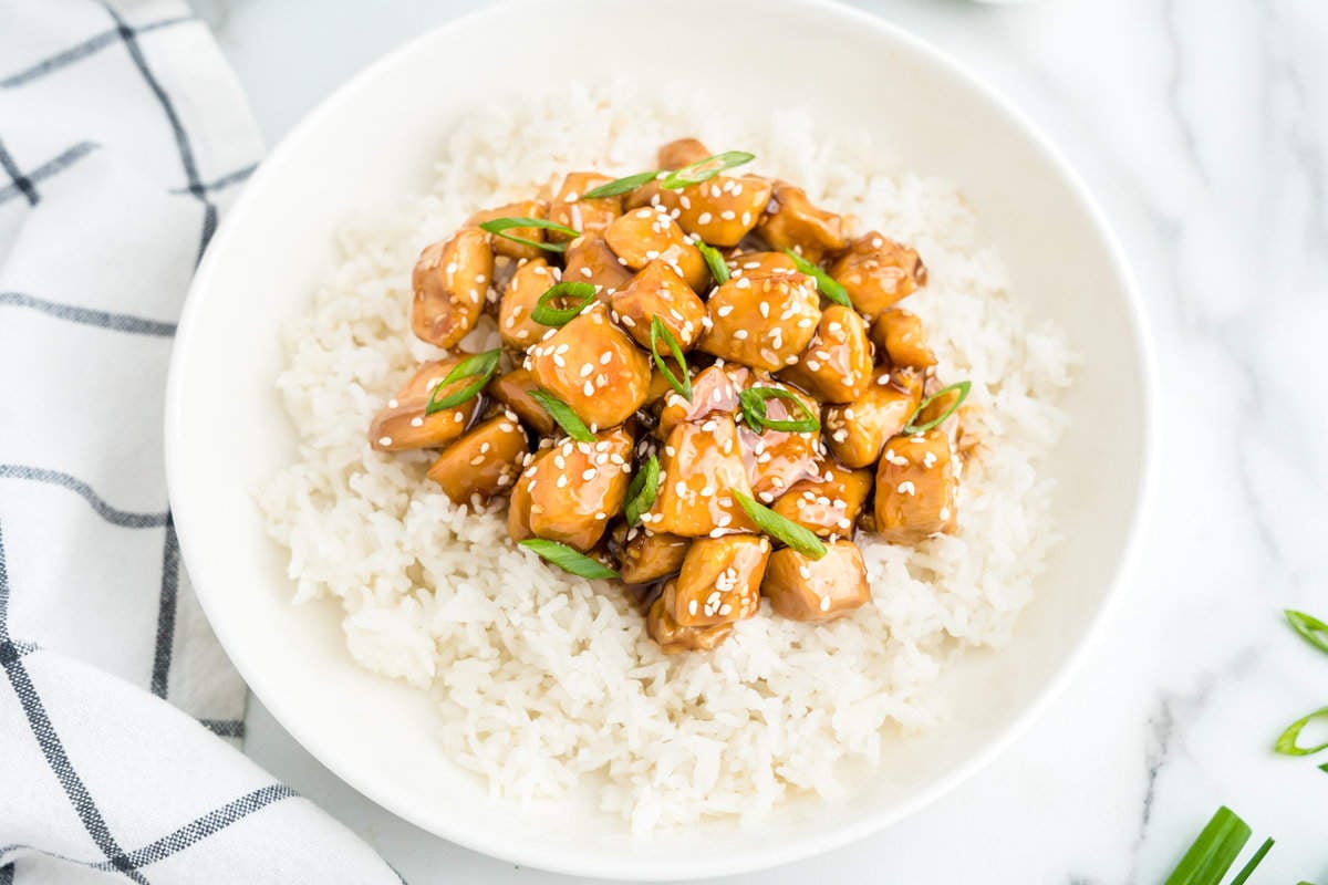 Teriyaki Chicken atop a bed of white rice in shallow serving bowl