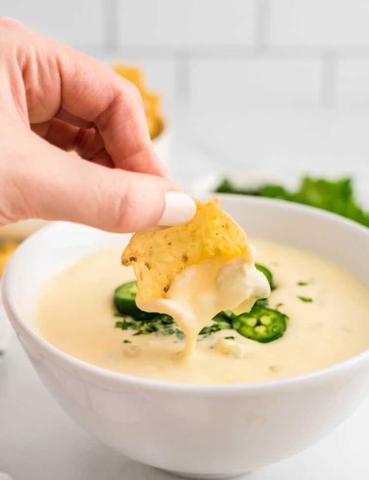 White Queso Dip in Serving Bowl with Tortilla Chip used for dipping