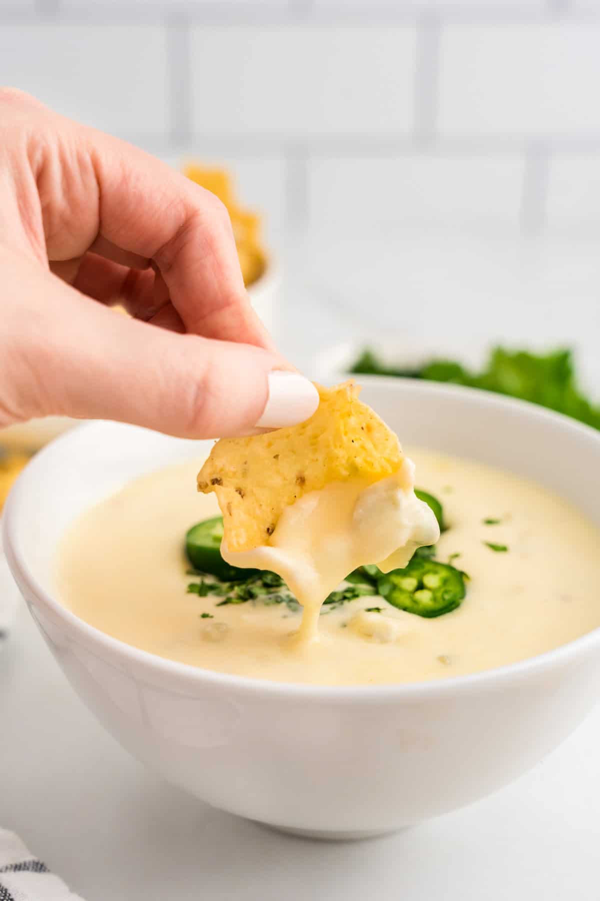 White Queso Dip in Serving Bowl with Tortilla Chip used for dipping