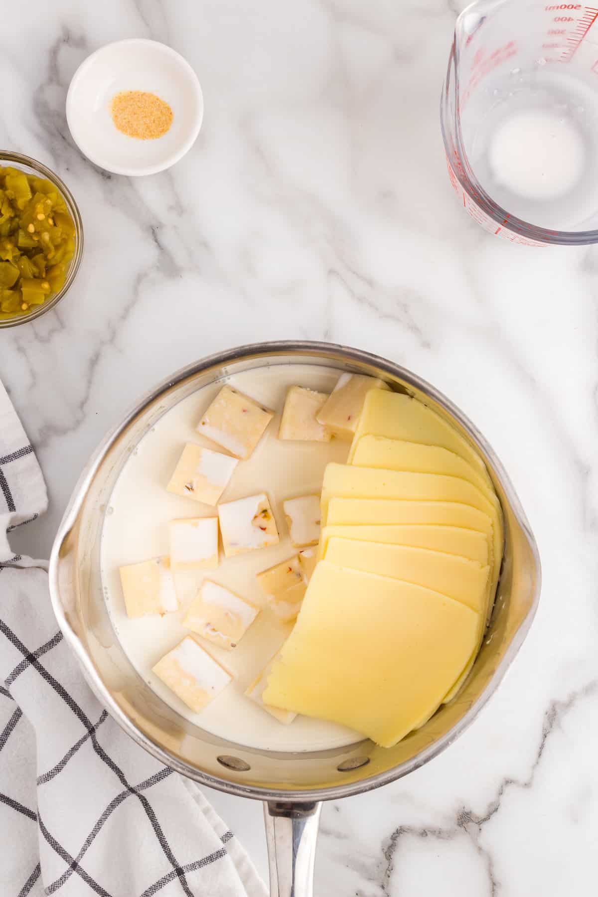 Cheeses and half and half in sauce pan for White Queso Dip recipe