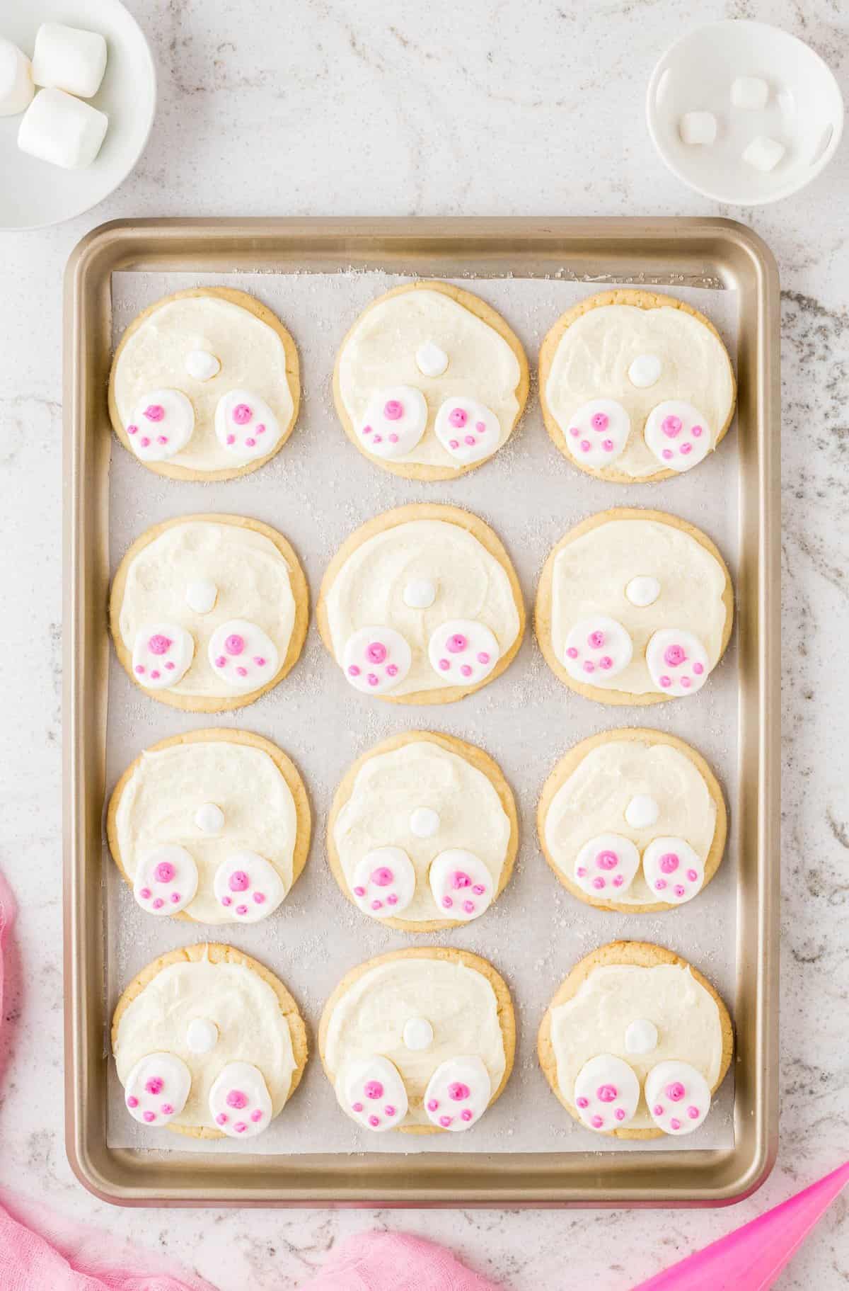 Put the pink icing in a piping bag and pipe a small heel pad and toe pads on the half marshmallows.