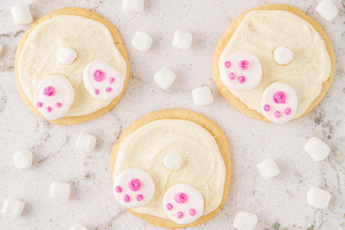 Three Completed cookies laying on a table with mini marshmallows around it.