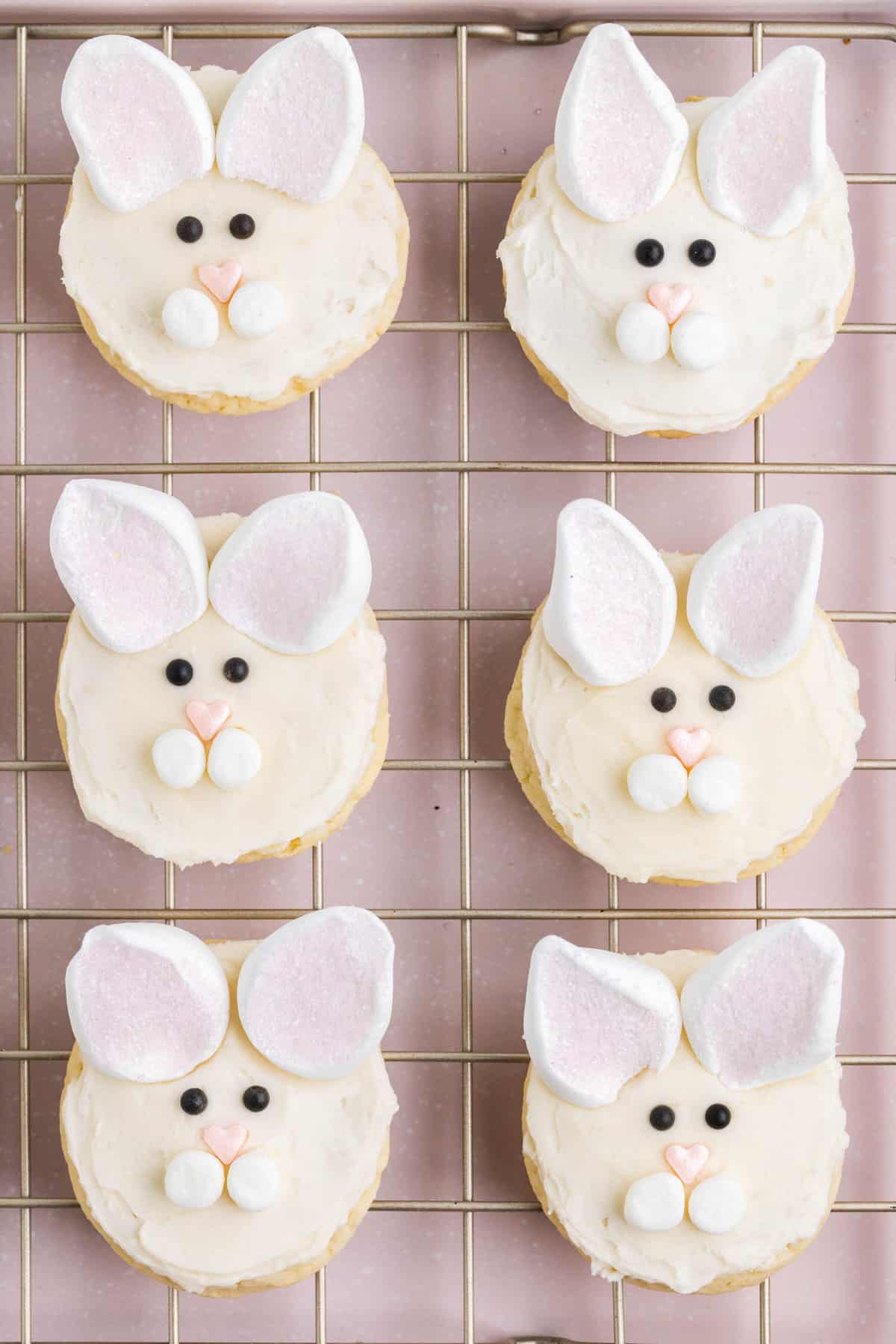 Add two of the marshmallow halves at the top of the cookie for the ears. Then add two black sprinkles below the ears and above the nose for eyes.