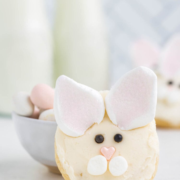 A Bunny Face cookie standing up right against a bowl filled with easter eggs.