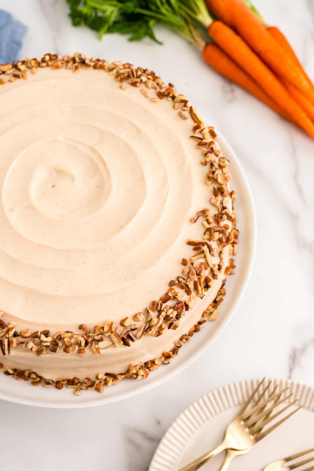 Frosting the two-layered Carrot Cake and lining with chopped pecans 