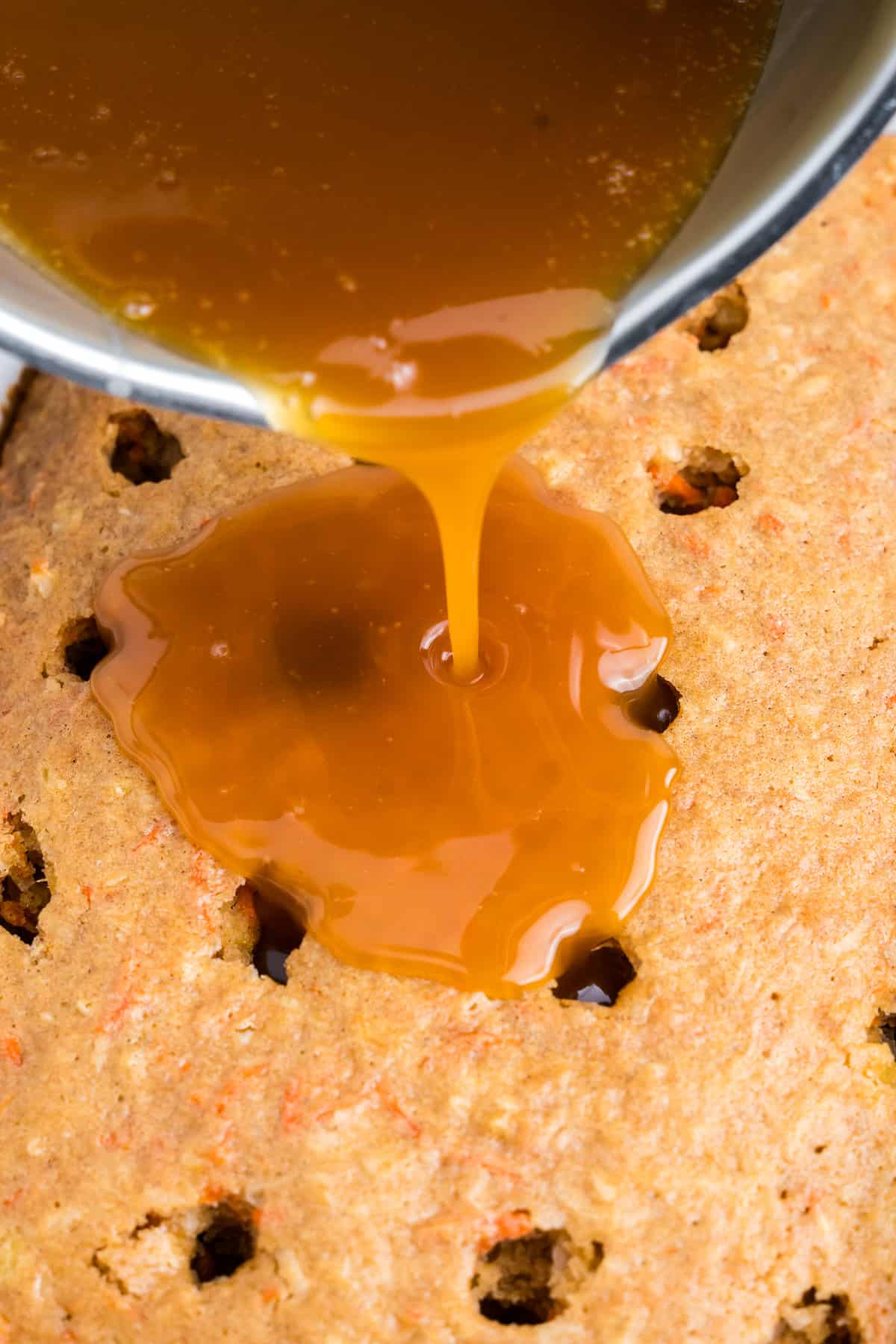 Pouring glaze in poked holes for Carrot Poke Cake recipe