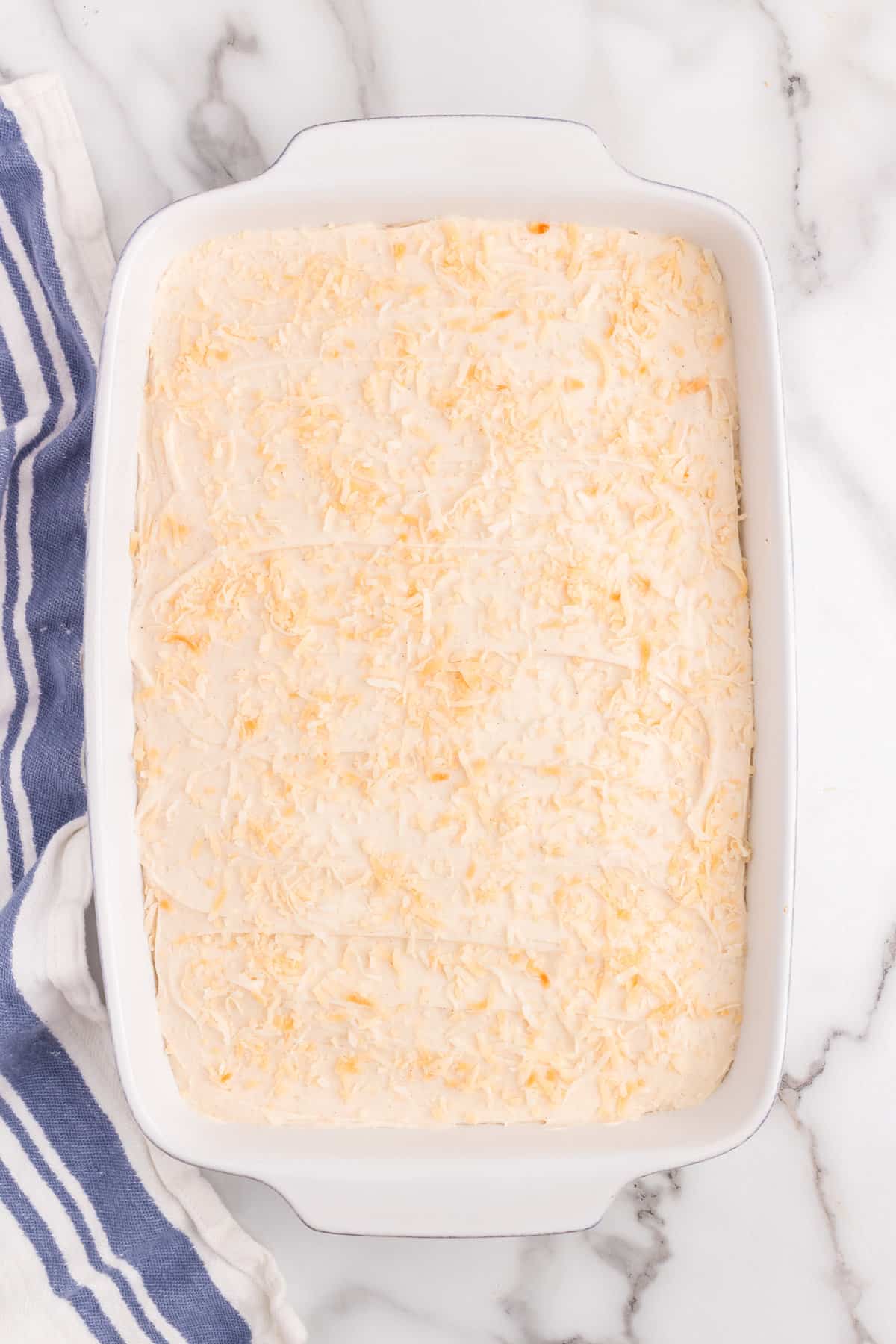 Generously covering Carrot Poke Cake with seasoned frosting