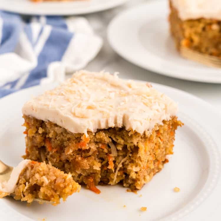 Square piece of Carrot Poke Cake on plate with one bite taken