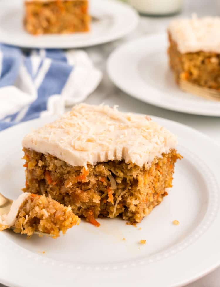 Square piece of Carrot Poke Cake on plate with one bite taken