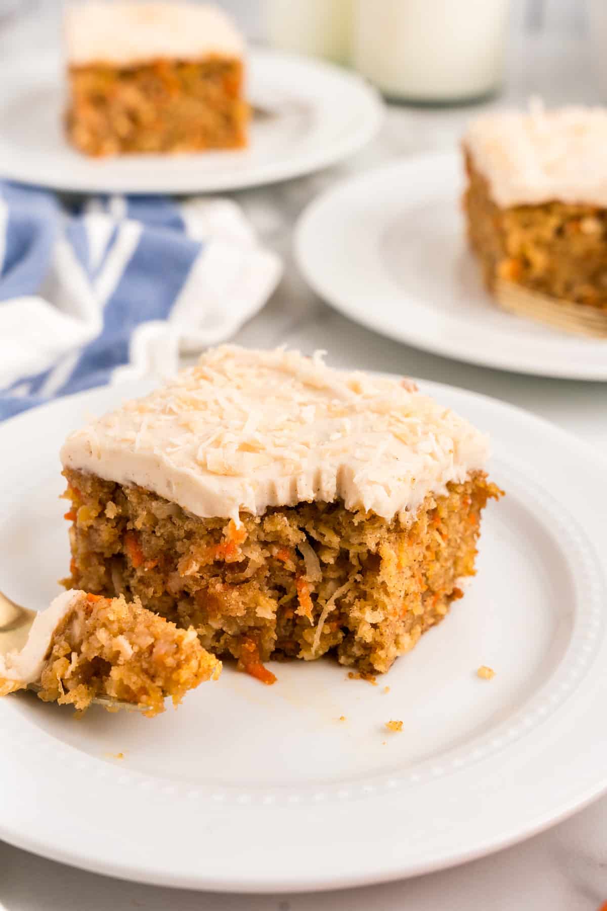 Square piece of Carrot Poke Cake on plate with one bite taken