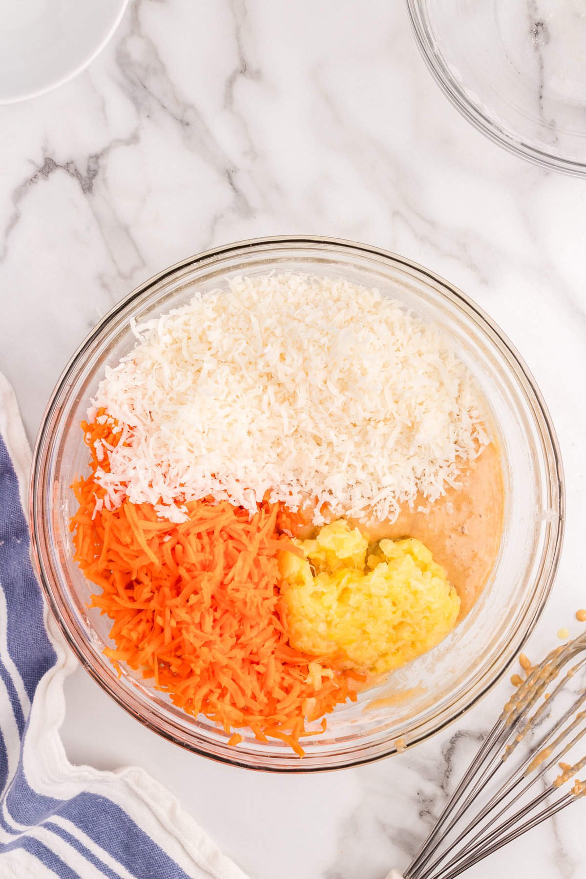 Adding shredded carrots and additional ingredients to mixing bowl for Poke Carrot Cake Recipe