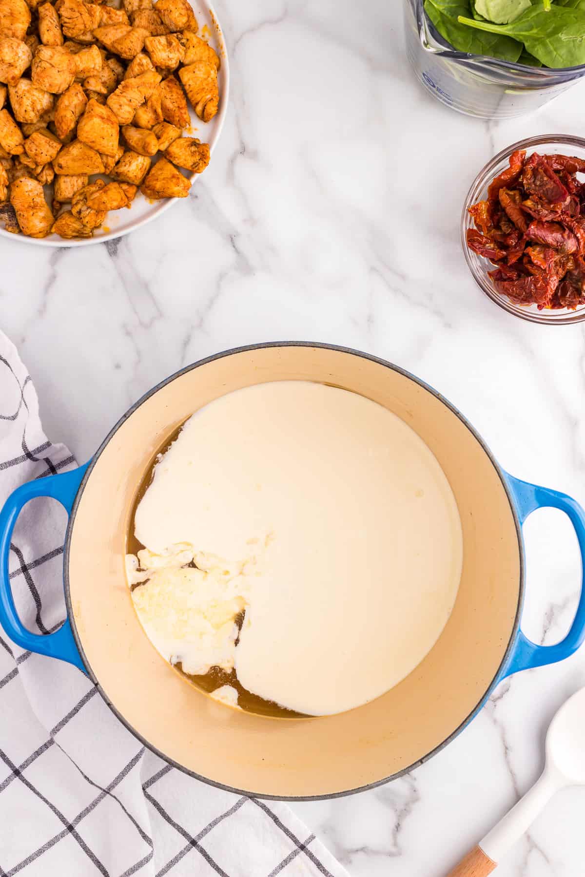 Preparing sauce for Creamy Tuscan Chicken Pasta in stovetop pot