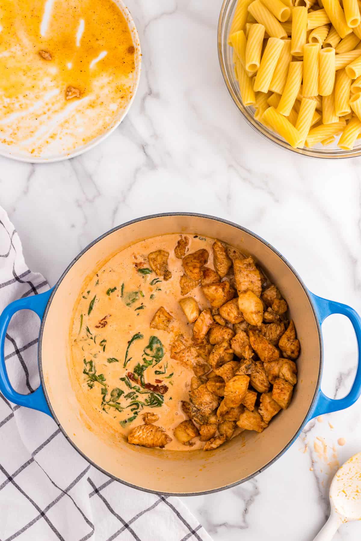 Stirring in seasoned chicken into Creamy Tuscan Chicken Pasta recipe