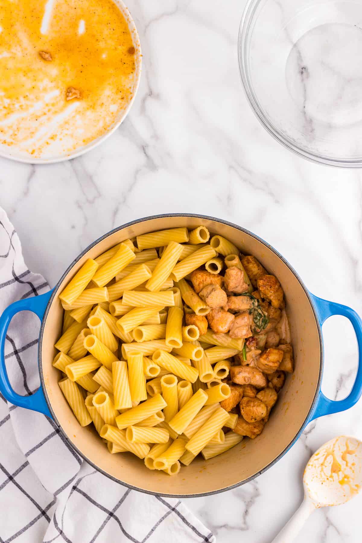 Adding pasta noodles to Creamy Tuscan Chicken Pasta mixture