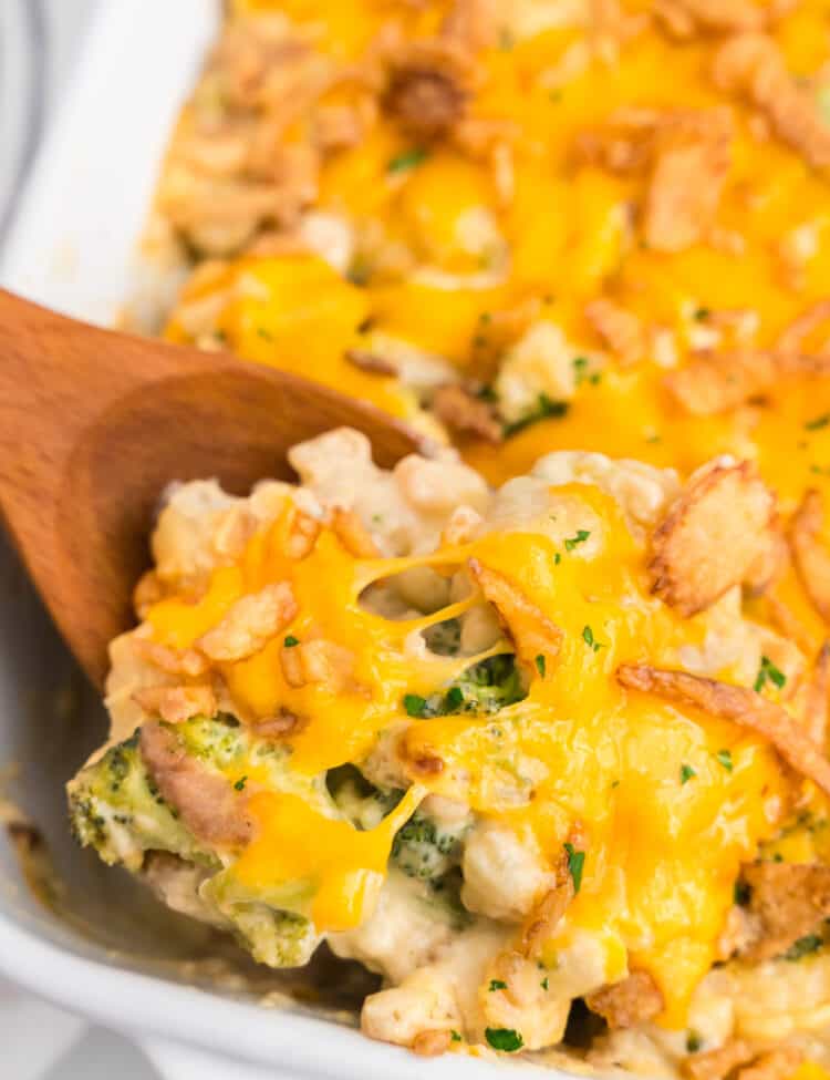 Broccoli Cauliflower Casserole in baking dish using wooden spoon to scoop