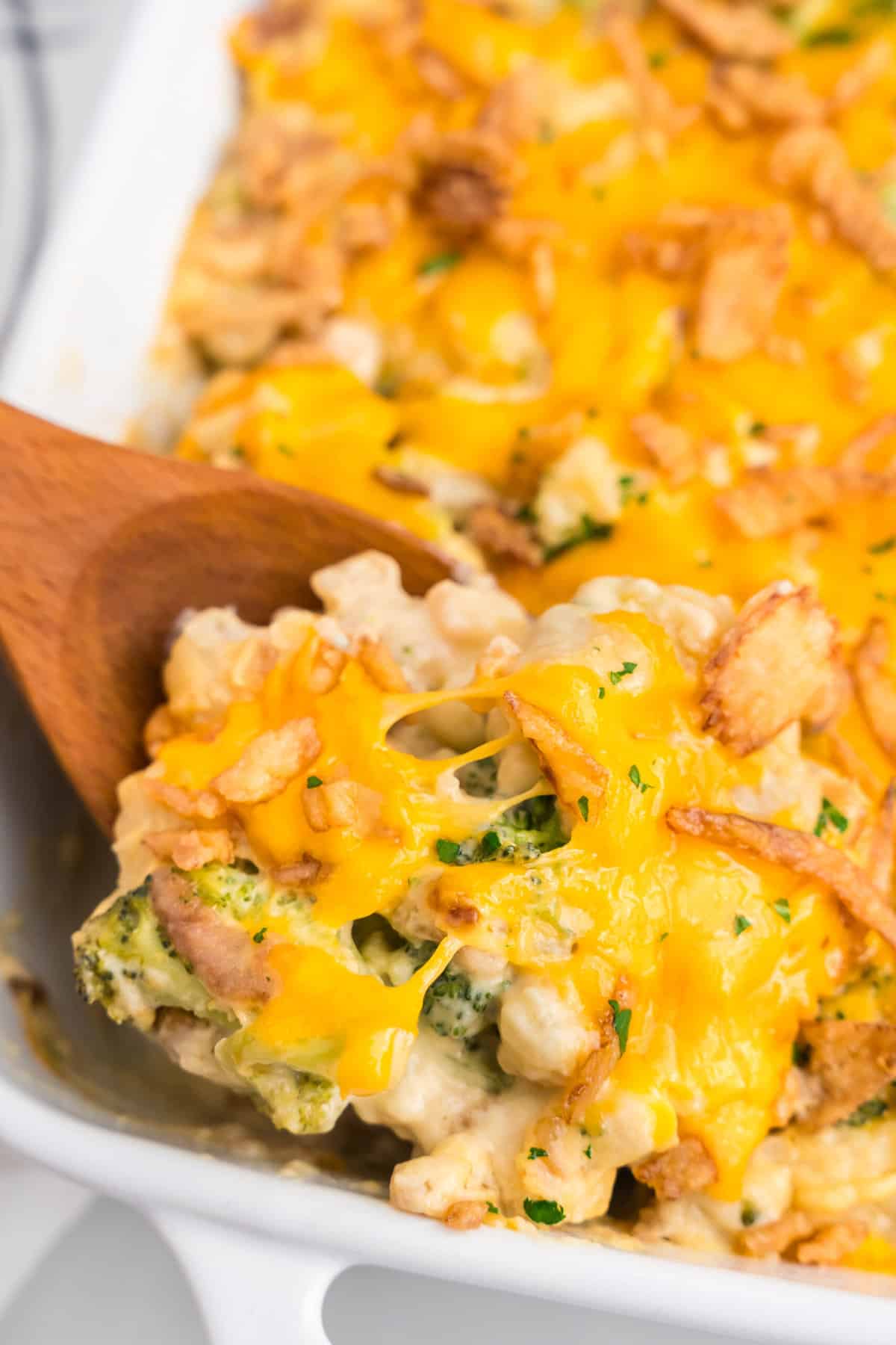 Broccoli Cauliflower Casserole in baking dish using wooden spoon to scoop