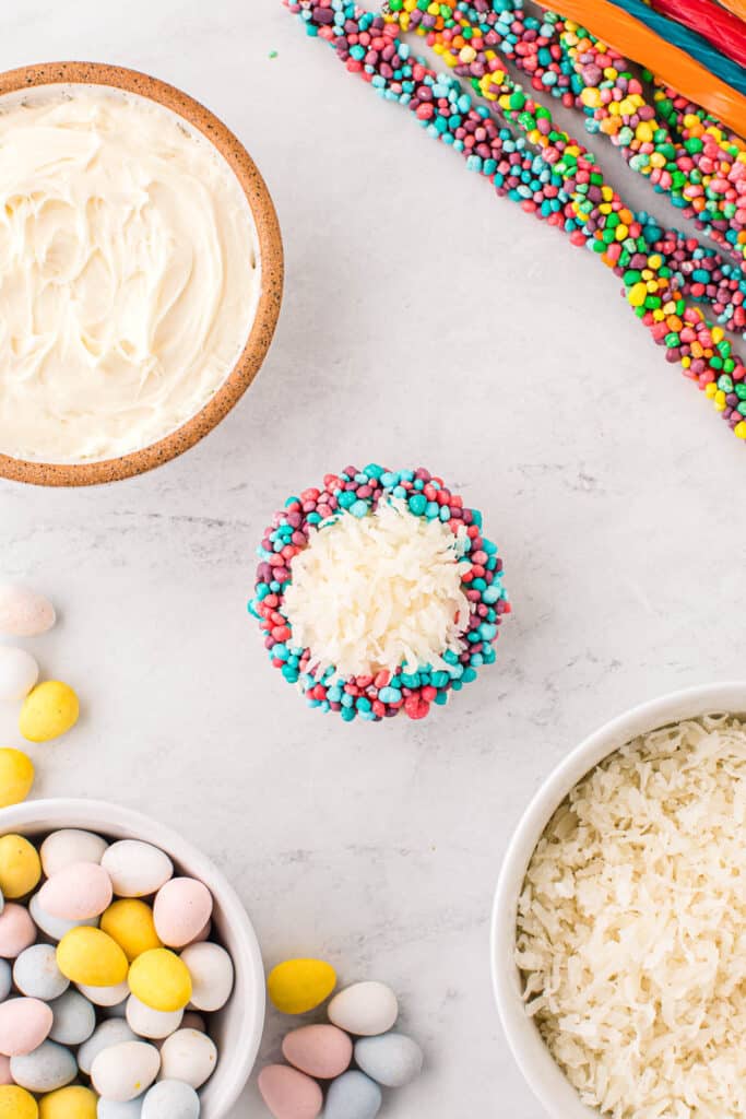 Wrap a nerd rope around the base of the top of the cupcake. Sprinkle some Coconut into the center of the nerd rope.