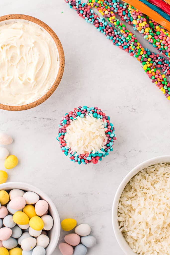 Wrap a nerd rope around the base of the top of the cupcake. Sprinkle some Coconut into the center of the nerd rope.