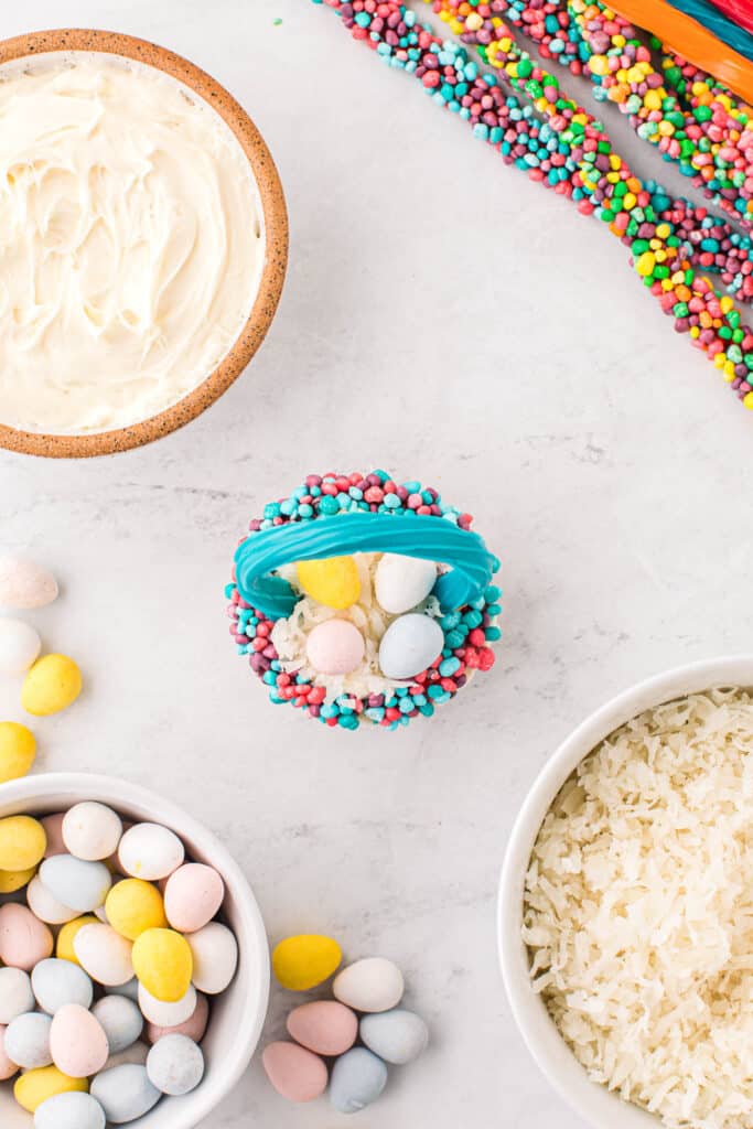 Place several eggs in the middle of the cupcake and place each end of a twizzler into the cupcake to make a handle.