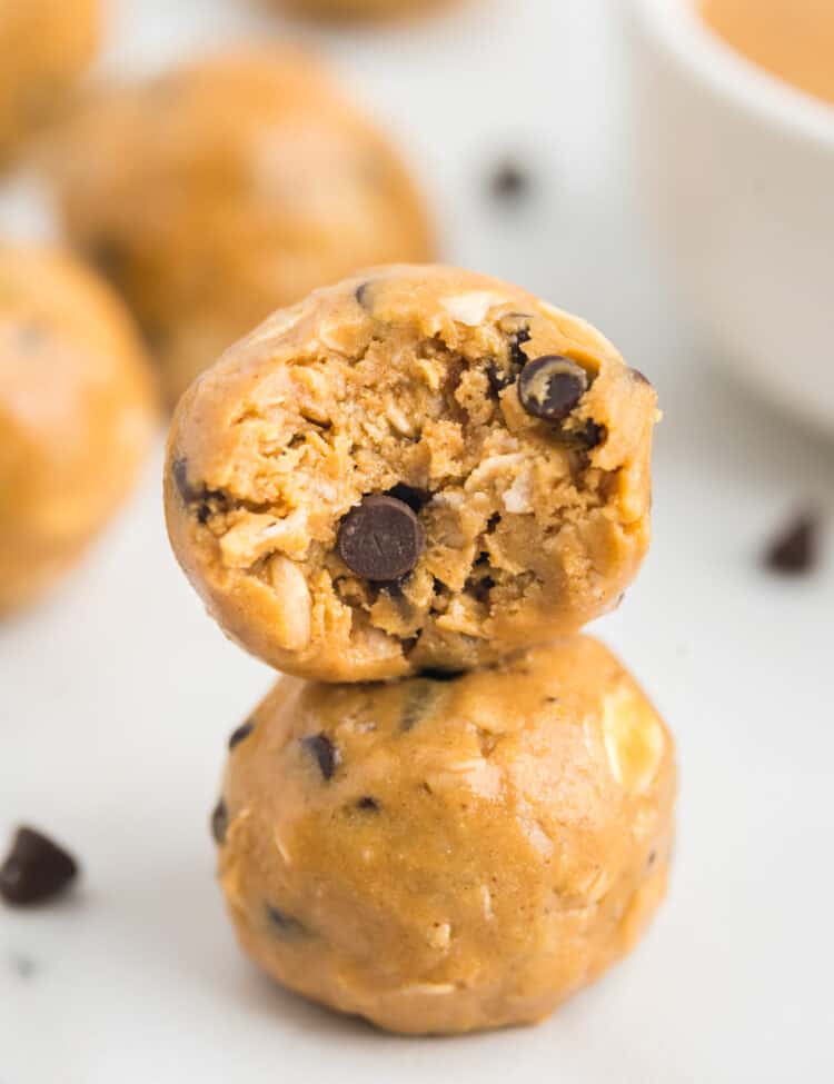 two energy balls stacked on top of one another, with a bite taken out of the top one.