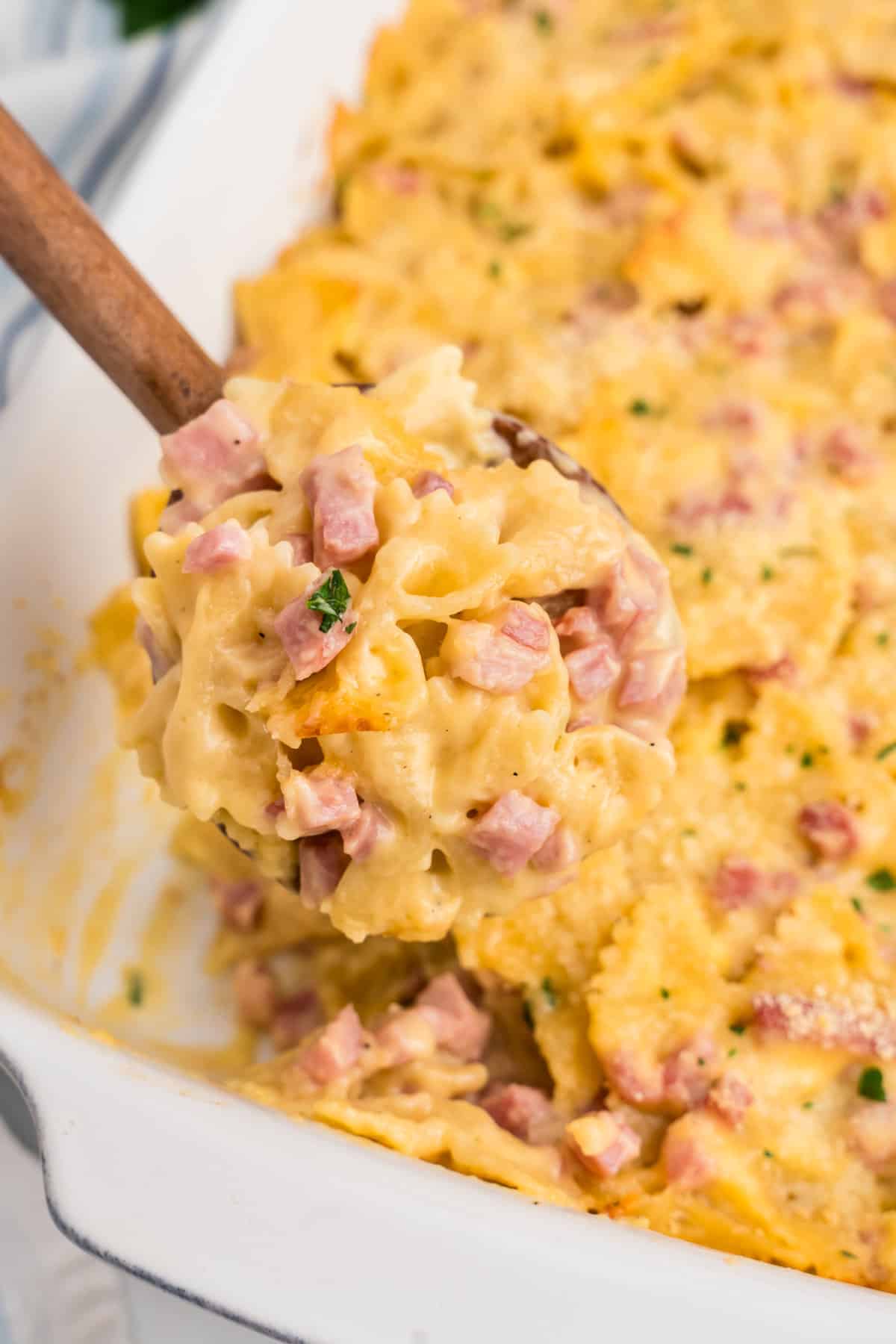 Cheesy Ham Casserole in baking dish with wooden spoon