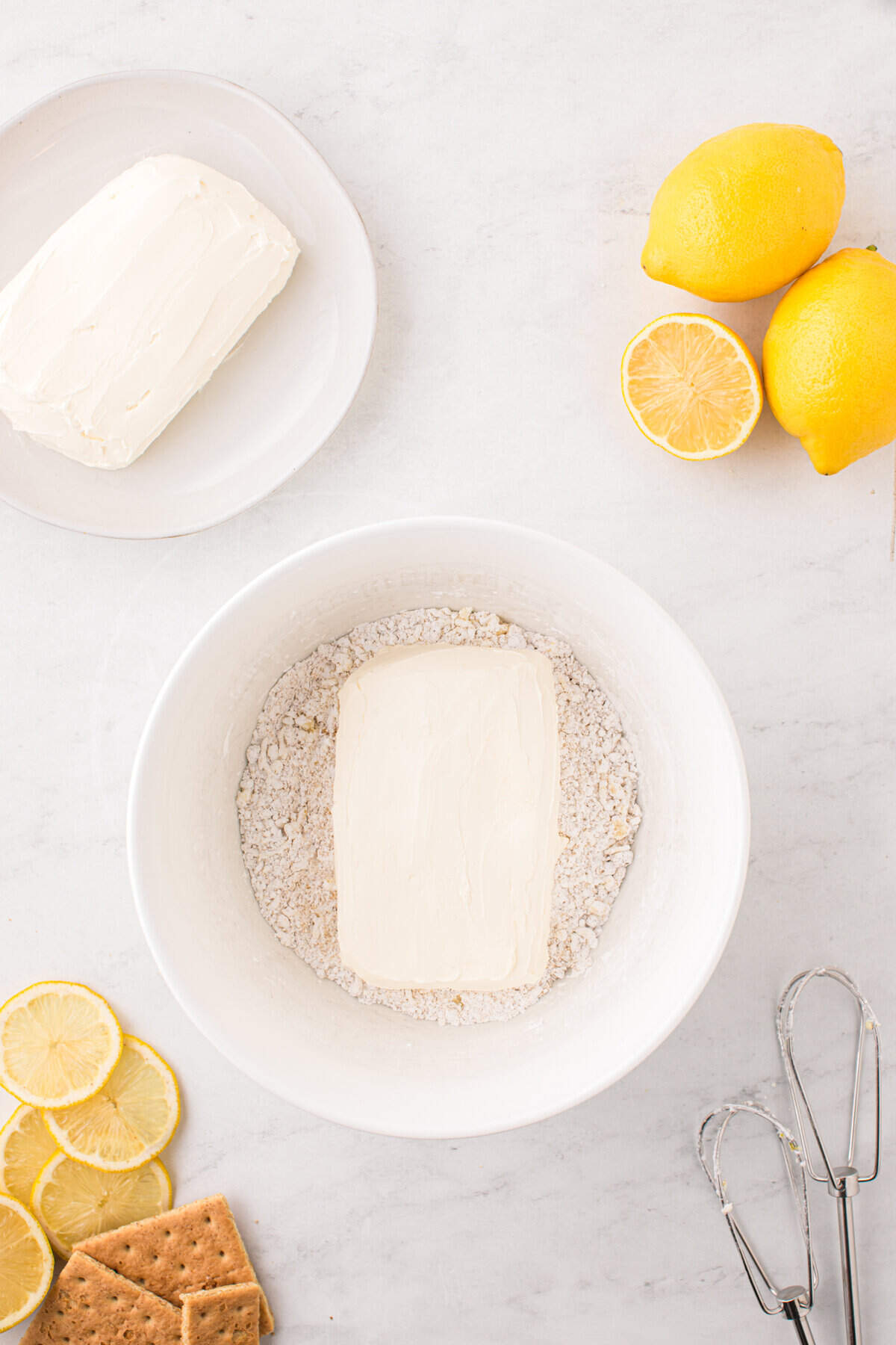 Adding softened cream cheese block to mixed Lemon Cheesecake ingredients