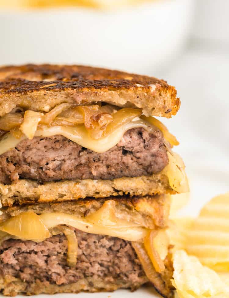 Patty Melt cut into two pieces stacked atop each other on plate