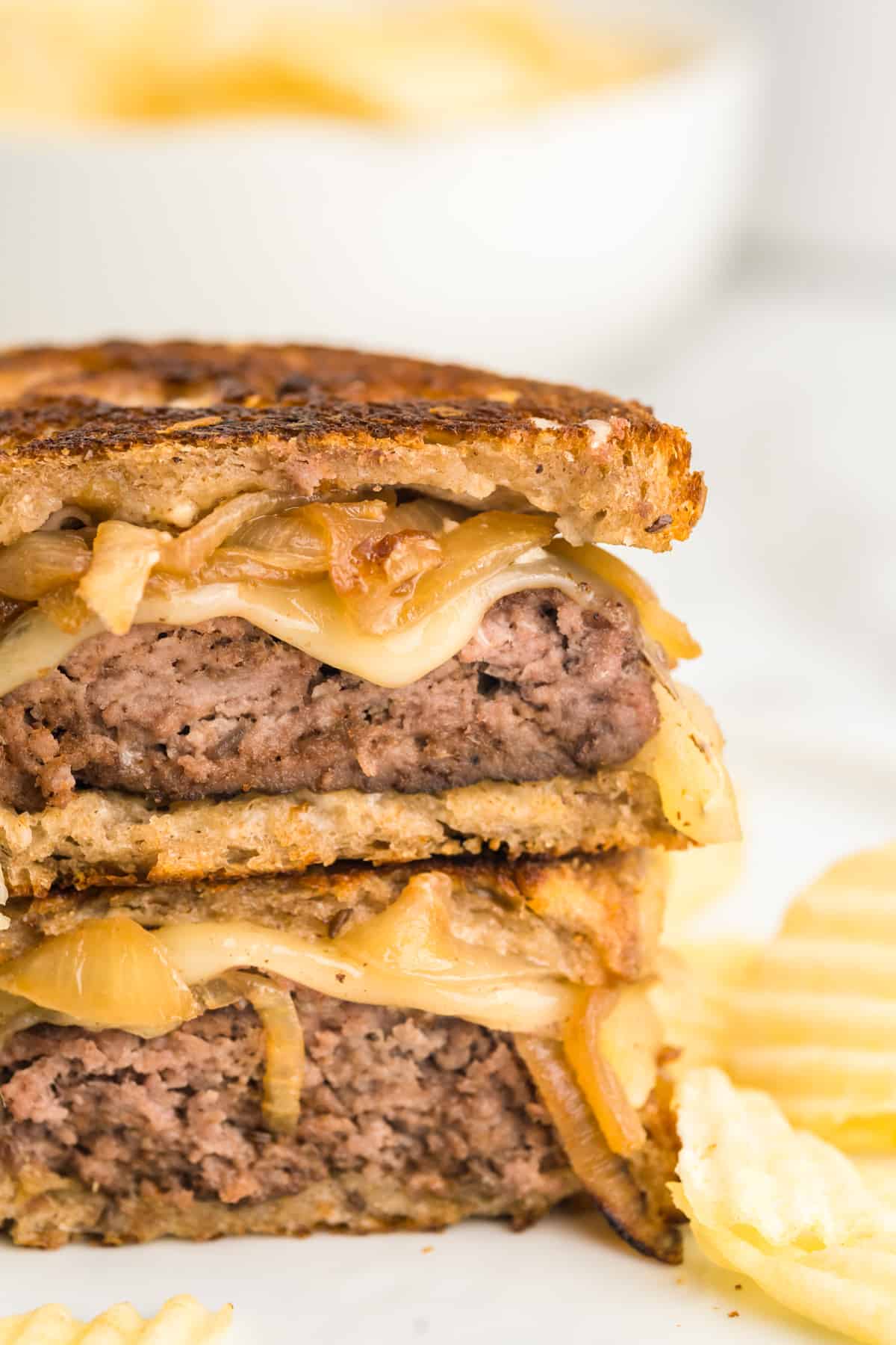 Patty Melt cut into two pieces stacked atop each other on plate