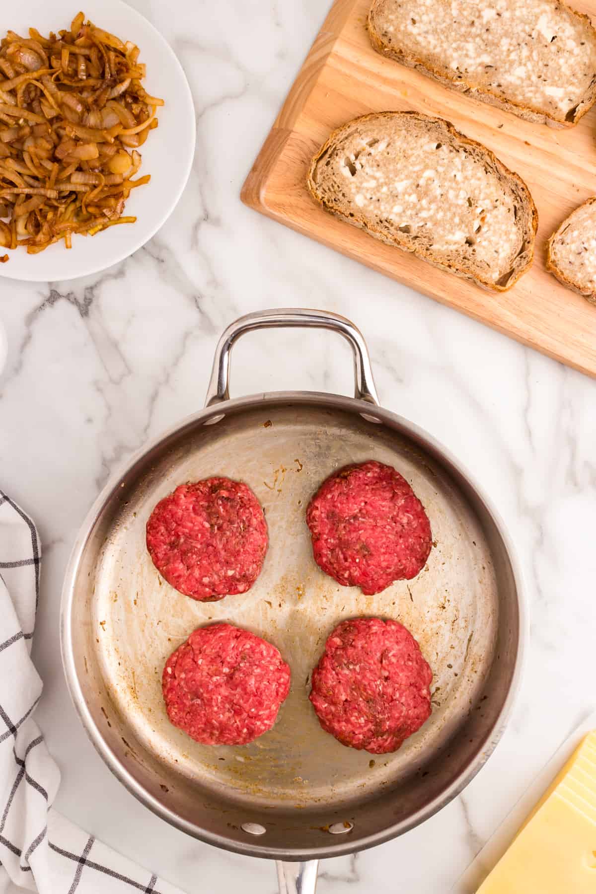Using stovetop skillet to cook seasoned hamburger patties for Patty Melt recipe