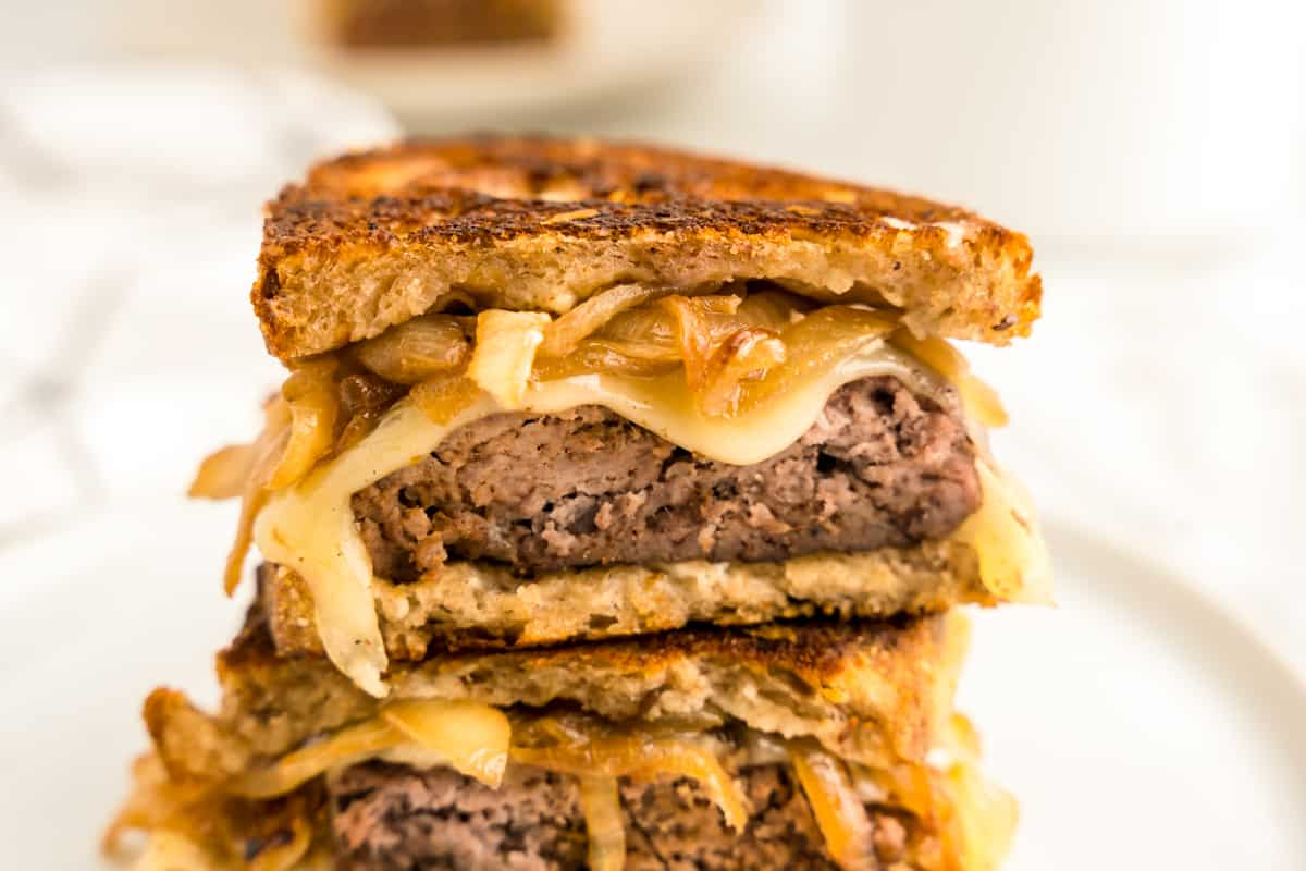 Patty Melt cut into two pieces stacked atop each other on plate