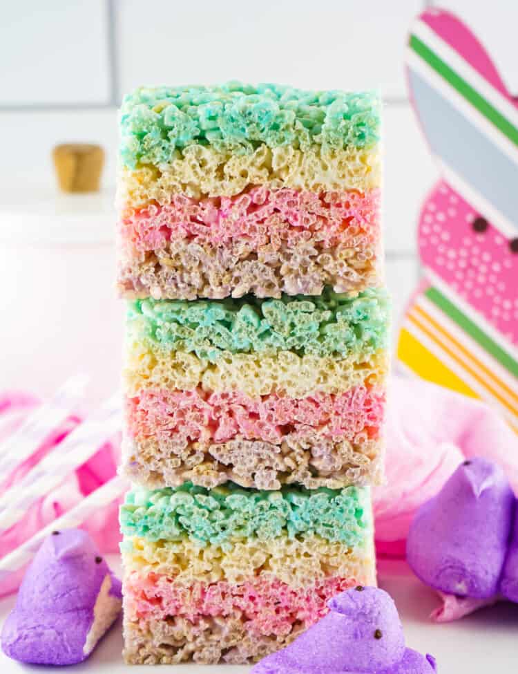 Stack of Three Rice Krispie bars with peeps on the plate at the bottom.