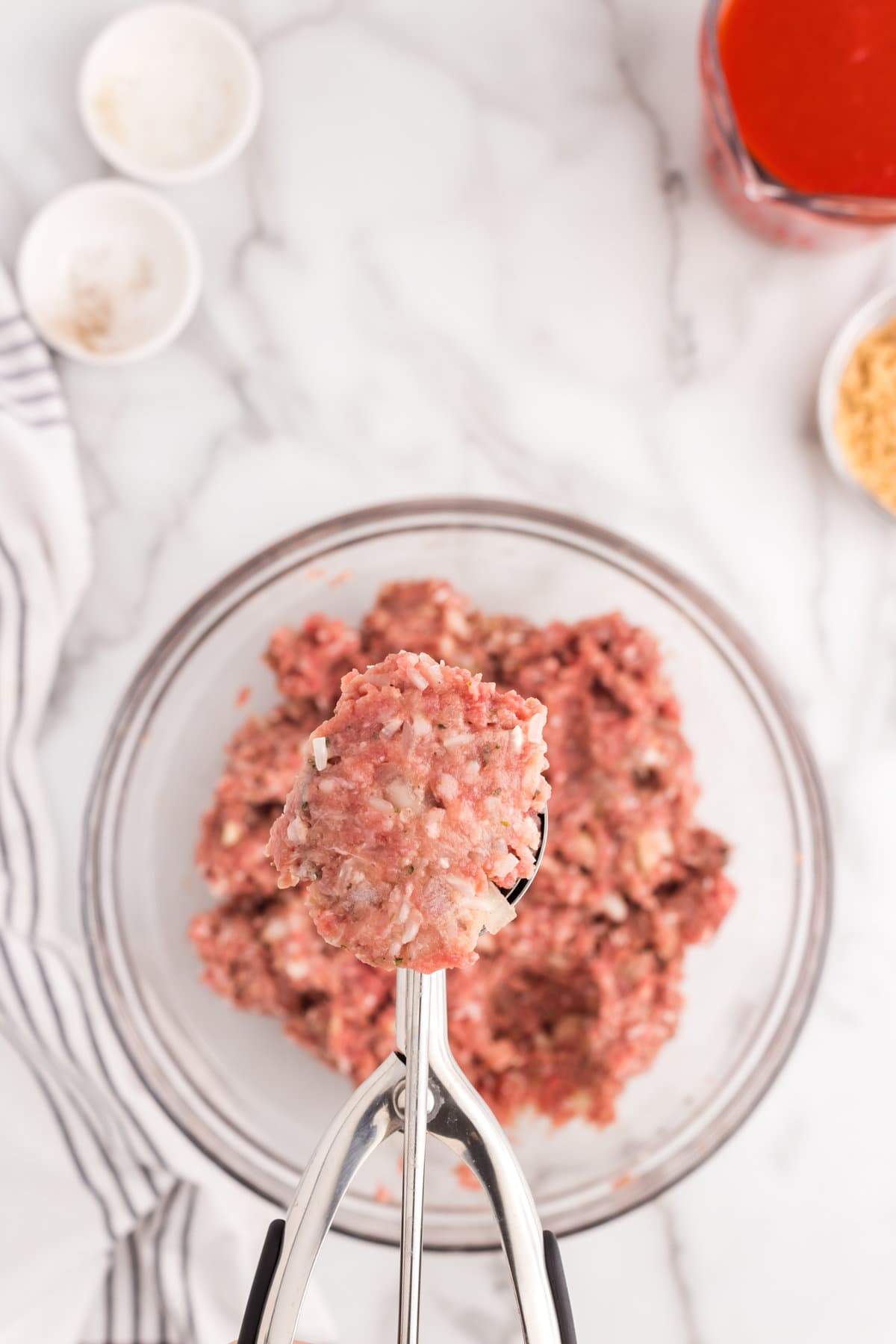 Using a scooper to scoop meatball mixture for Porcupine Meatballs recipe
