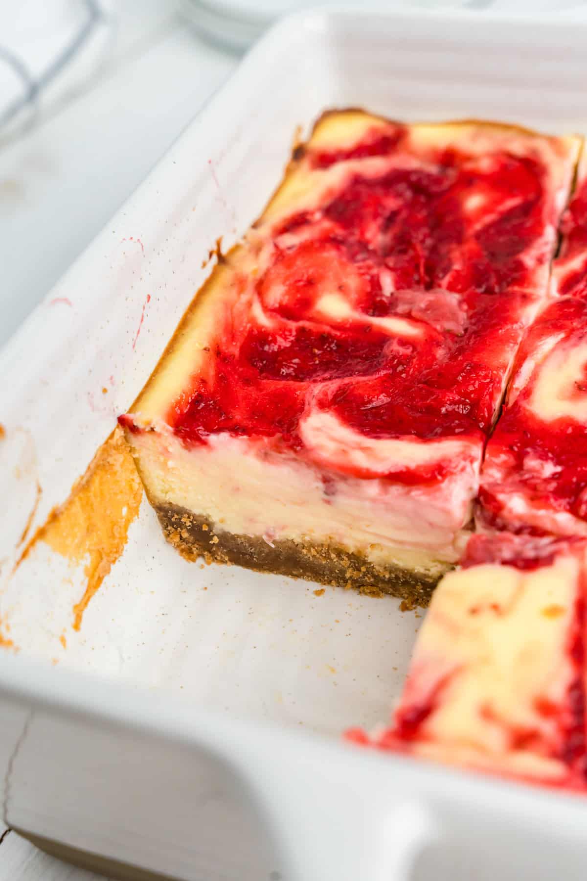 Cutting Strawberry Cheesecake Bars into squares in baking dish