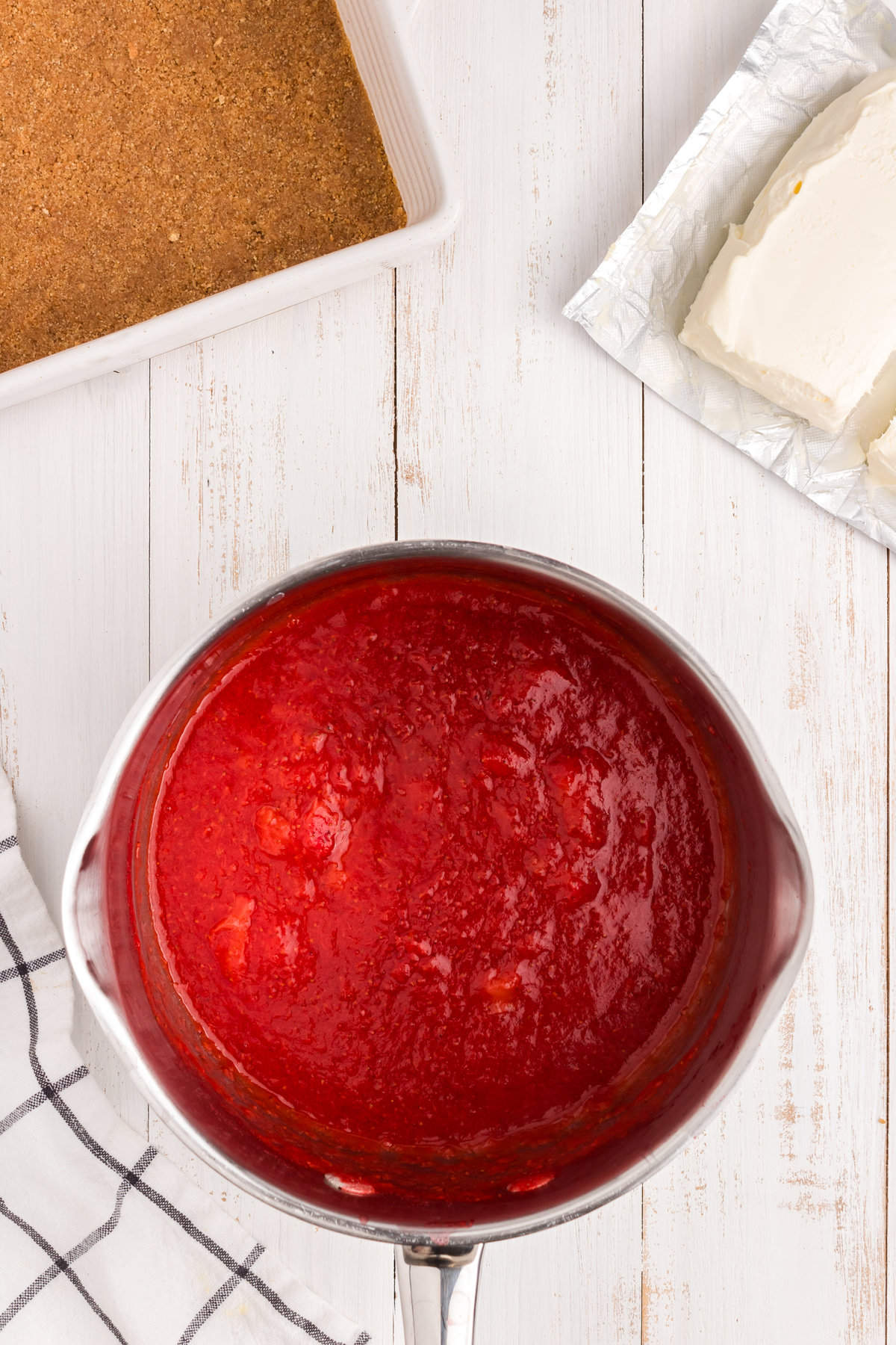 Ingredients for strawberry sauce in stovetop saucepan for Strawberry Cheesecake Bars recipe