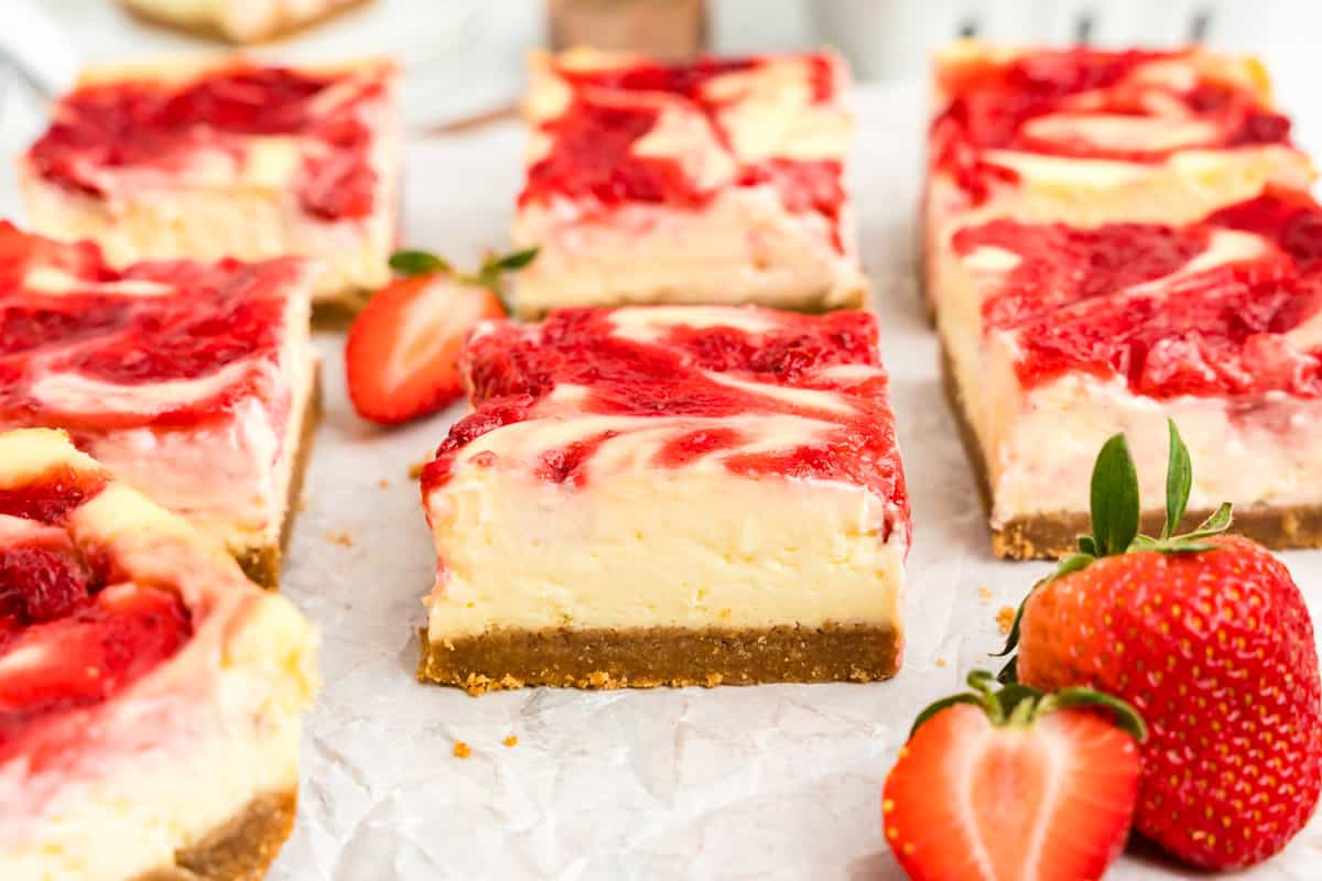 Strawberry Cheesecake Bars cut into squares arranged on parchment paper