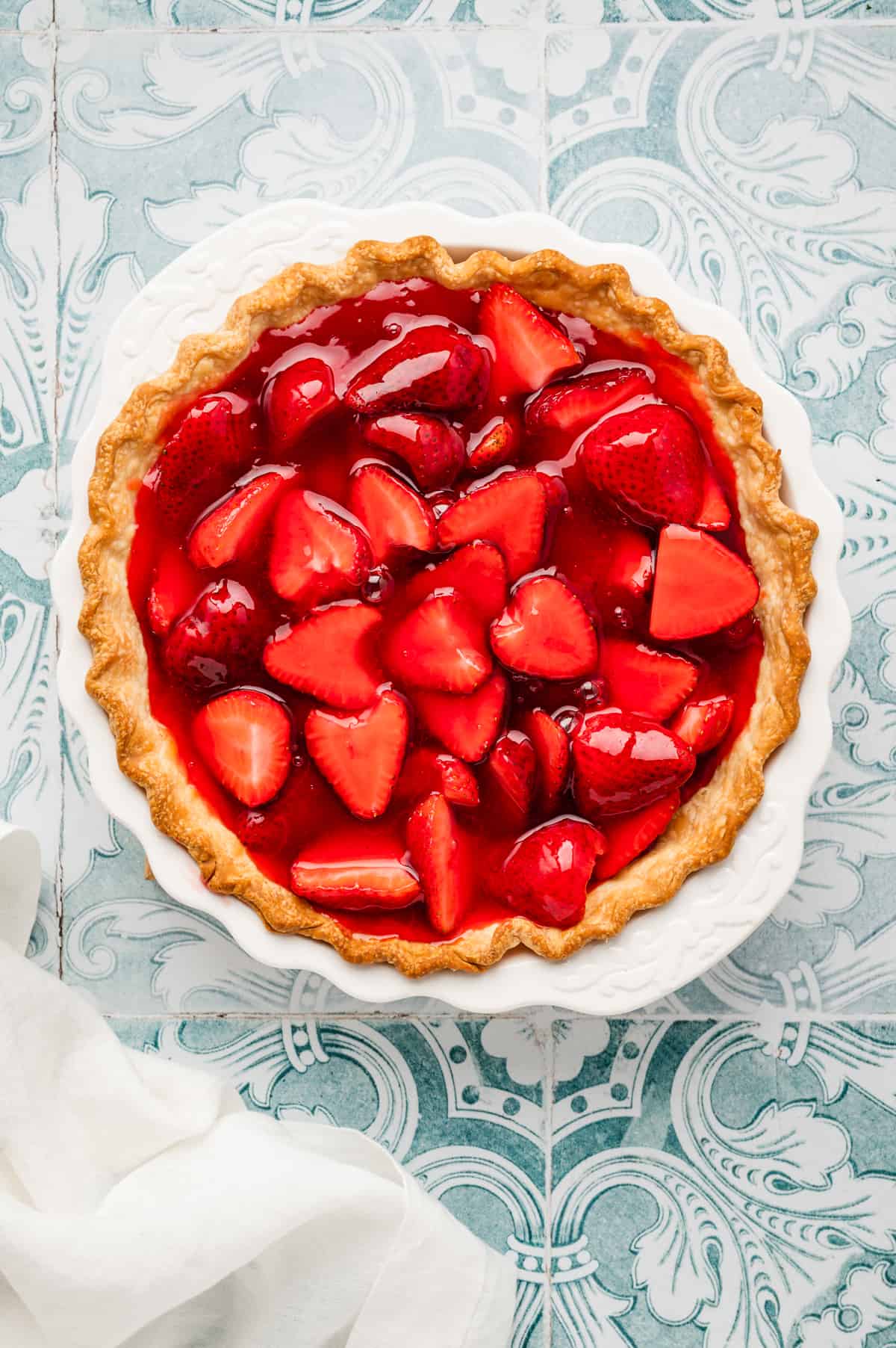Adding Jell-O mixture over strawberries in crust-lined pie pan for Easy Strawberry Pie