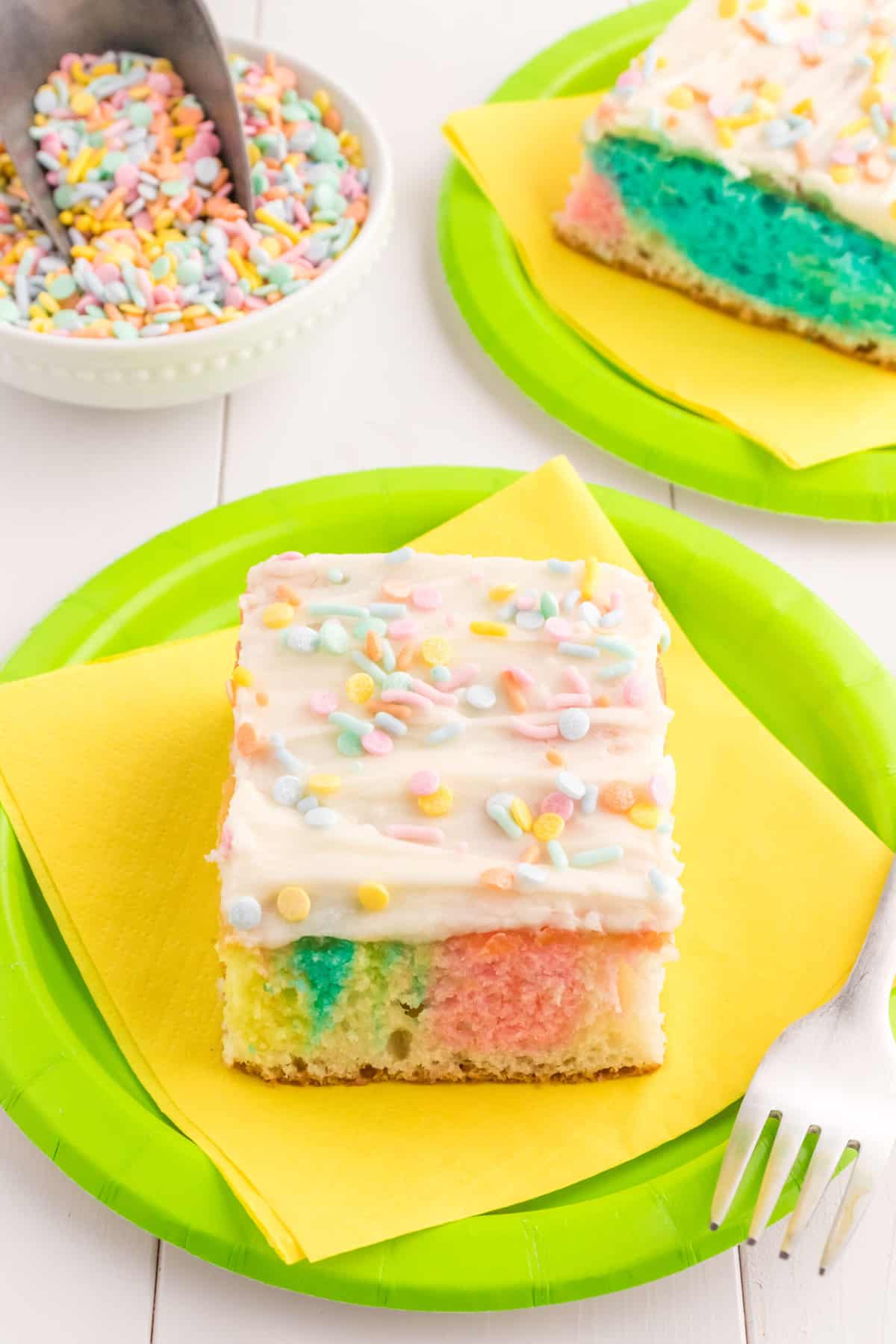 a Piece of cake sitting on a green plate with a yellow napkin.